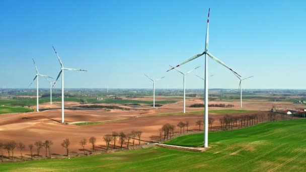 Великі вітрові електростанції в полі з невеликим оранкою в сонячний день — стокове відео