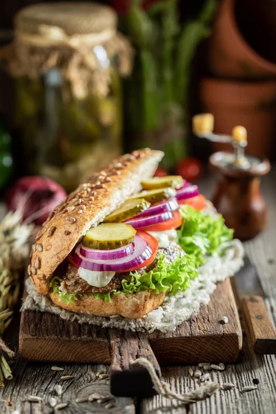 Ízletes szendvics sült sertésfélnyakkal, uborka, hagyma — Stock Fotó