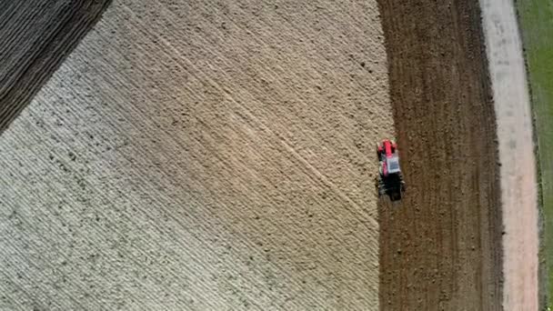 Czerwony ciągnik orki wiosna pole, Polska, widok z lotu ptaka — Wideo stockowe