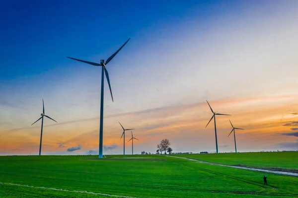 Flying above stunning wind turbines at dusk on green field — Stock Photo, Image