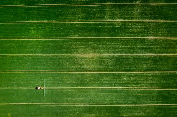 Voando acima do trator pulverizando os pesticidas no campo, Polônia — Fotografia de Stock