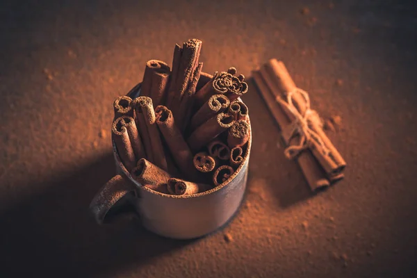 Cinnamon bark and powder in an old metal mug — Stock Photo, Image