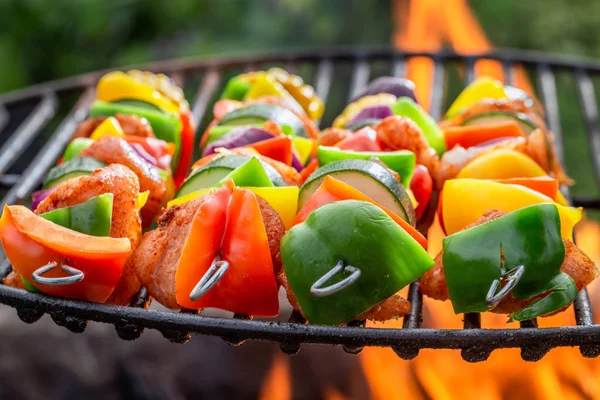 Closeup of hot skewers on grill with vegetables and meat — Stock Photo, Image