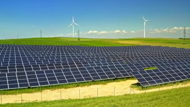 Solární panely a větrné turbíny na zeleném poli s modrou oblohou, letecký výhled, Polsko — Stock video