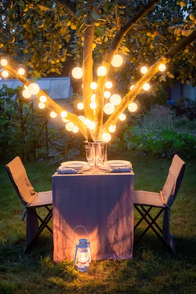Mesa iluminada para dois no jardim de verão verde — Fotografia de Stock