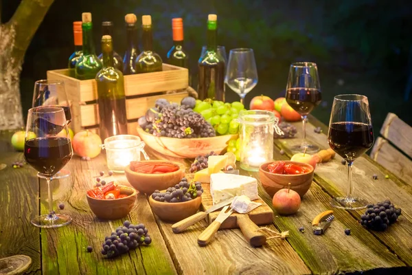 Closeup of table with snacks and wine in illuminated garden — Stock Photo, Image