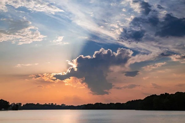 Geweldige zonsondergang aan het meer met zonnestralen in wolken — Stockfoto