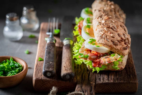 Sanduíche saboroso com bacon, cebolinha e ovos — Fotografia de Stock