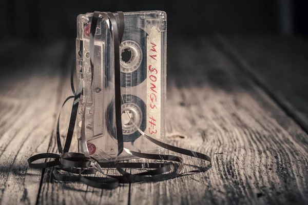 Ahşap masa üzerinde çıkarılmış bant ile bir kaset — Stok fotoğraf