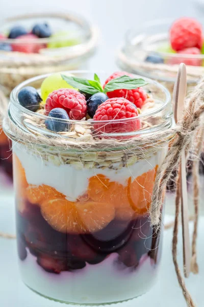 Крупный план мюсли в банке с ягодами и йогуртом — стоковое фото
