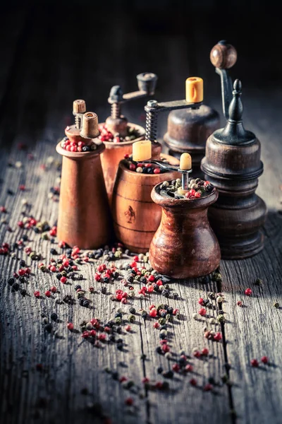 Pepper mills with red and black pepper on wooden table — Stock Photo, Image