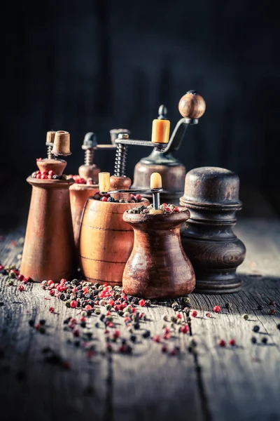 Pepper mills with black and red pepper on wooden table — Stock Photo, Image