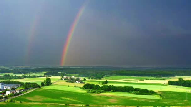 Flygbild över regnbåge över gröna fält efter en storm — Stockvideo