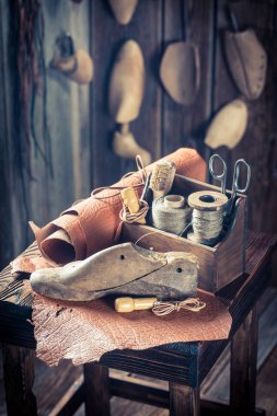 Closeup of shoemaker workshop with tools, leather and shoes clipart
