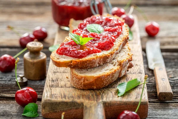 Sandwich with fresh cherry jam on wooden table — Stock Photo, Image