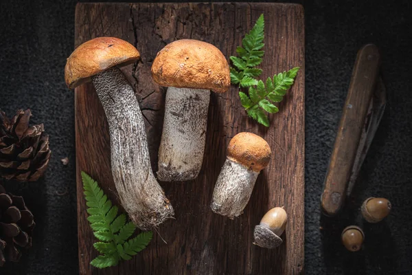 Cogumelos selvagens cheios de sabor e aromáticos em tábua de madeira — Fotografia de Stock