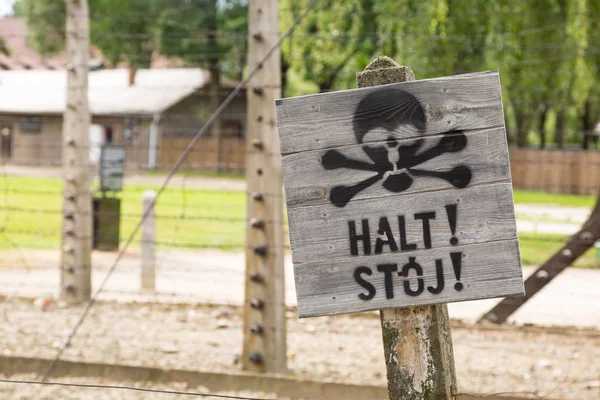 アウシュビッツ ポーランドのナチ集中キャンプの有刺鉄線の前に頭蓋骨 と警告サイン ストックフォト