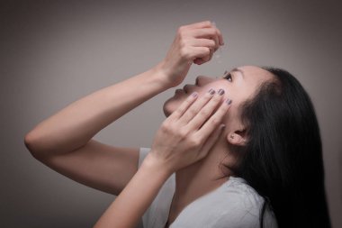 Asyalı Genç kadın göz damlası göz tedavisi için kullanır. Kızarıklık, Kuru göz, alerji ve göz kaşıntı