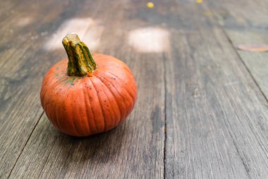 Küçük turuncu kopya alanı ile basit ahşap plaka üzerinde oturan kabak yuvarlak. Cadılar Bayramı festivali için dekorasyon