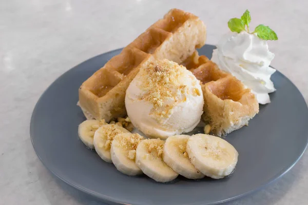 Waffles with vanilla ice cream, banana split & salted caramel sauce, serving on gray plate, ready to eat