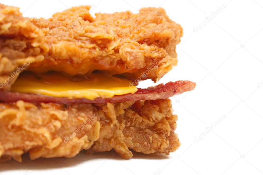 Close up of the bunless burger features crispy bacon and slices of cheese sandwiched between two breaded chicken fillets, isolated on white