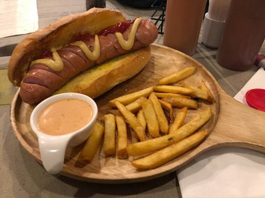 Sarı Hardal, Sos ve Patates Kızartması ile Hot Dog, ahşap tepside hizmet vermektedir. yemeye hazır. Fast food konsepti