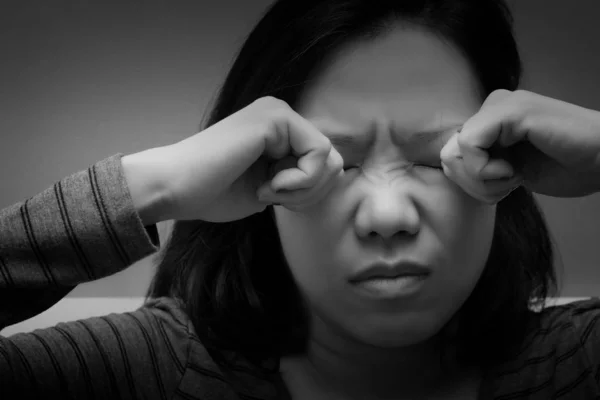 Asian woman rubbing her eyes by two hands. Concept of eye\'s problem, dust allergy, dry eye, watery, itching or contact lenses problem. black and white tone