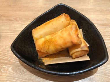 Deep Fried Spring Rolls siyah tabakta servis ediliyor, domuz kıyması, kibrit dilimli havuç, dilimlenmiş lahana ve ince dilimlenmiş soğan ile yapılan klasik aperatif yiyecekler hepsi sarılıp altın olana kadar kızartıldı.