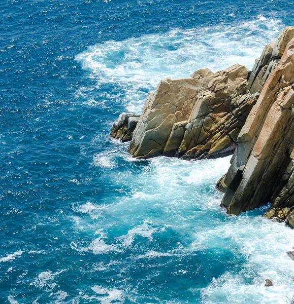Голубое море с каменистым берегом в солнечный день — стоковое фото