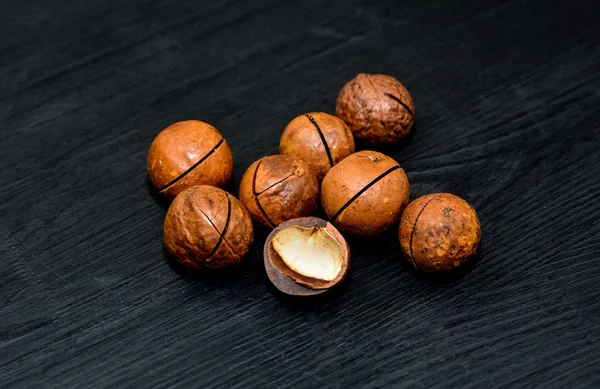 Macadamia nuts on black wooden background