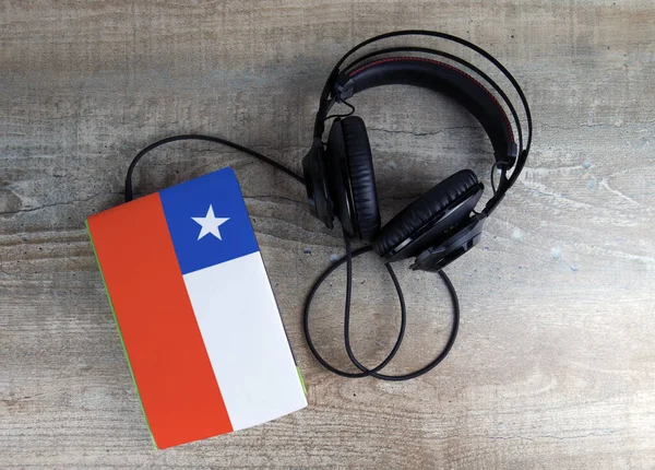 Headphones and book. The book has a cover in the form of Chile flag.
