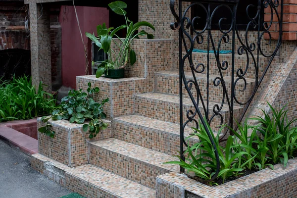 Evin verandasında ince bir korkuluk var, mozaik fayanslarla kaplı.