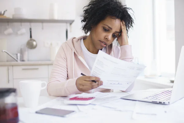 年轻的非洲裔美国女性有严重的财政问题 感到压力 而管理家庭预算在厨房餐桌上 — 图库照片