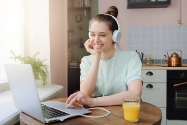 Arkadaş ya da aile ile messenger app, ile onun favori müzik kapalı mutfakta oturmuş güzel genç gülümseyen kadın söz