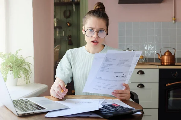 Verbaasd Jonge Vrouw Zit Aan Keukentafel Met Rekeningen Van Nutsbedrijven — Stockfoto