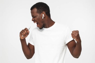 Gri arka plan üzerinde izole boş beyaz t gömlek giymiş en sevdiği şarkı, şarkı genç Afro-Amerikan yakışıklı