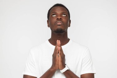 Sorunun cevabını yüksek kuvvetlerinden bekliyor sanki yukarıda Afrikalı-Amerikalı adam birbirlerini için bir dua, hareketle preslenmiş palm ile ayakta gri arka plan üzerinde izole arıyorsunuz