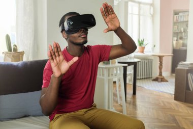 Yatay dikey genç hipster Afrikalı adamın parlak rahat kıyafetler ve avuç içi sanki video oyunu alternatif uzayda uçan yayılan sanal gerçeklik gözlük takıyor bakıp dahil odaklı