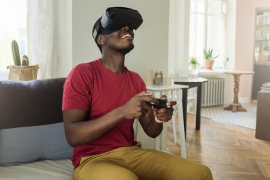 Afrika gencin yardımıyla sanal gerçeklik kulaklık ve oyun denetleyicisi arıyor, onun düz iskambil video oyunları resimde kapalı fotoğraf memnun ve mutlu bir şekilde gülümseyerek oyun süreci ile heyecanlı