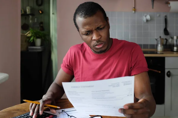 英俊的非洲裔美国人的特写照片解决他在家里的财务问题检查文件中的信息和账单核实计算结果用铅笔在手认真看 — 图库照片