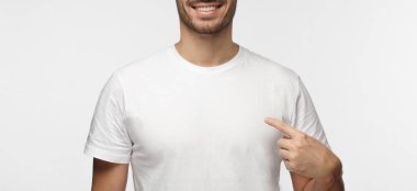 İşaret parmağı, kopya alanı için reklam, onun boş Beyaz tişört gösteren gülümseyen güzel adam gri arka plan üzerinde izole