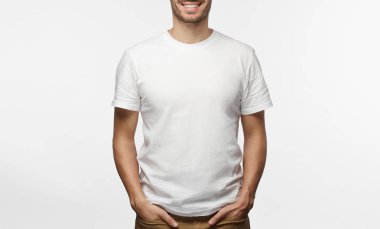 Yakışıklı adam beyaz tshirt gülümseyen, gri arka plan üzerinde izole eller cepler poz ayakta