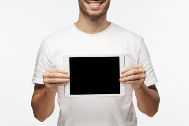Tablet tutarak ve ürün veya hizmet danışmanlık sanki boş ekran mutlu gülümseme ile gösterilen rahat kıyafetler içinde duran gri arka plan üzerinde izole olumlu adam stüdyo resmi