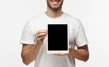 Boş tablet ekran sunan bir gülümseme ile izleyiciler, boşaltmak için reklam mal veya apps için resimde izole üzerinde gri arka plan ile trendy şeffaf gözlük, genç adam