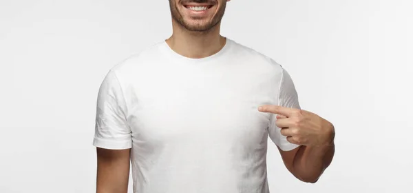 灰色の背景に分離された広告テキストやイメージ 立っての空スペースで空白の白い シャツで人差し指で指している若い男 — ストック写真
