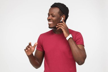 Favori şarkı listesi ile boş zamanını harcama, kablosuz kulaklık kullanarak, bedeni hareketli gri arka plan üzerinde izole Afrikalı-Amerikalı adam sevinç, memnun ve gülümseyerek bakıyor hissediyorum yatay atış
