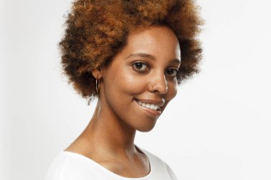 Yatay closeup headshot Afrikalı Amerikan Bayan gri arka plan üzerinde izole seksi esmer gülümseyen, döndü başkanı olan ve onun dudak ısırma genç