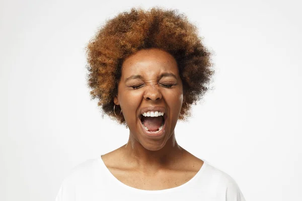 闭上眼睛尖叫的肖像疯狂的非洲裔美国妇女在灰色背景下的空白白色 T恤衫中隔离 — 图库照片