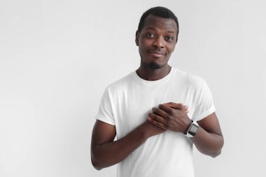 Tür yürekli dost güzel siyah adam şefkat gösterir. Portre pozitif genç Afro-Amerikan erkek gülümseyen, elleri göğsünde tutar, sempati ifade eder