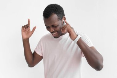 Pembe tişörtlü, kablosuz kulaklık ve akıllı genç Afro-Amerikan yakışıklı onun en sevdiği şarkıyı dinlerken, dans, ile kapalı gözler gülümseyen saatler